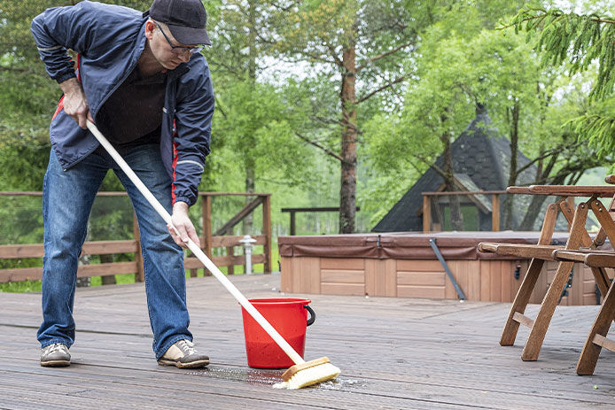 A man cleaning a deck with a brush and soapy water