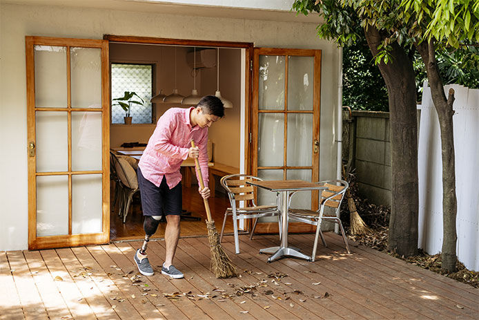 A man sweeping leaves off a deck