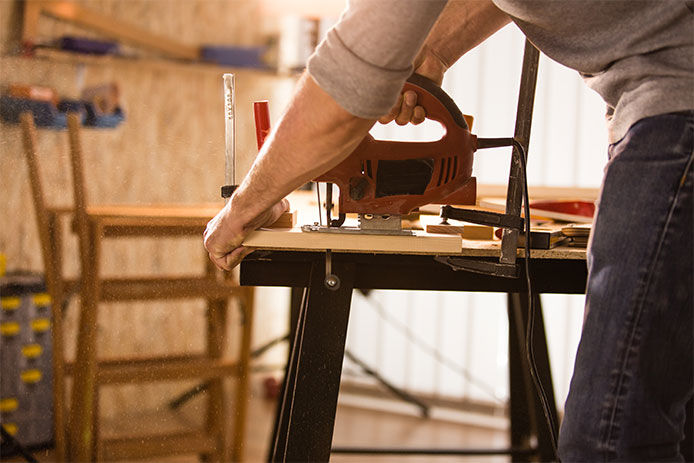 Carpenter cutting a wood using jigsaw cutter