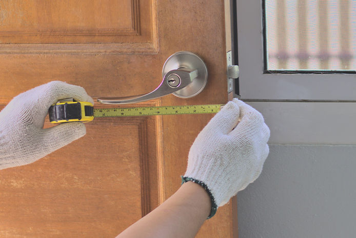 Person measuring door handle with gloves on