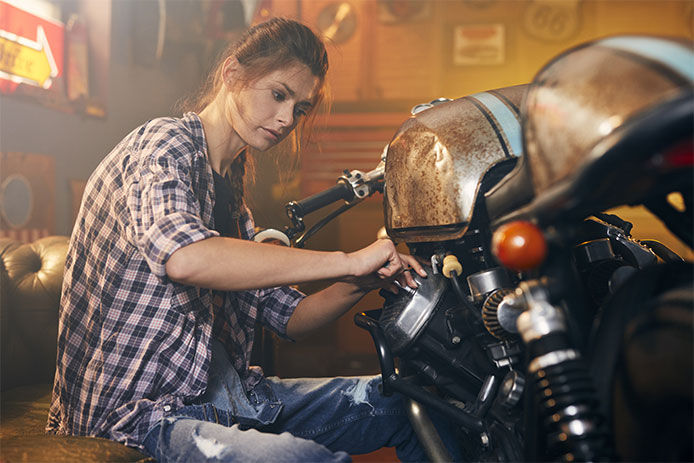 Woman working on a motorcycle in her garage
