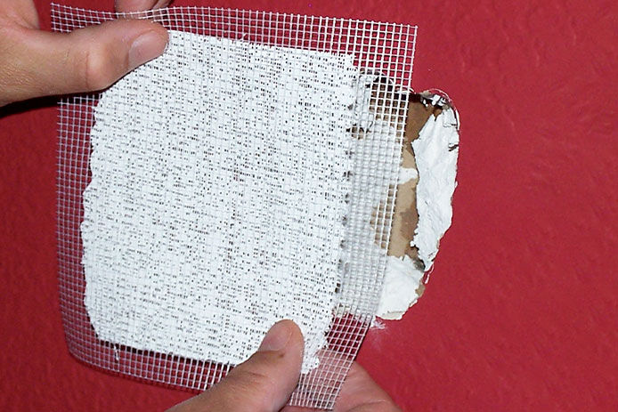 Placing a wire mesh drywall patch over a hole in the wall