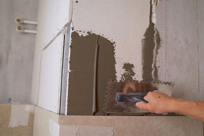 Applying morter to the backer board of shower surround