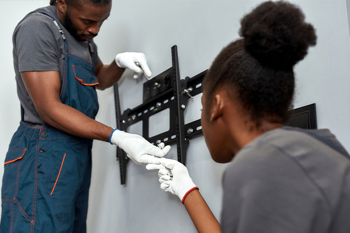 Close view African man and woman during TV wall brackets installation work. Team work concept.