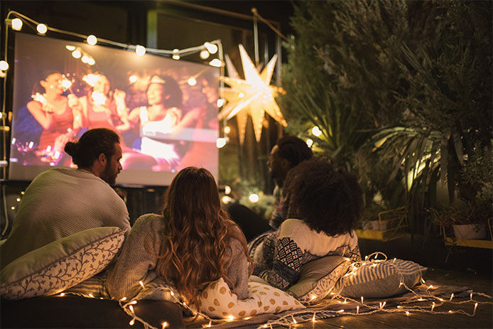 People outside watching a movie on a projector