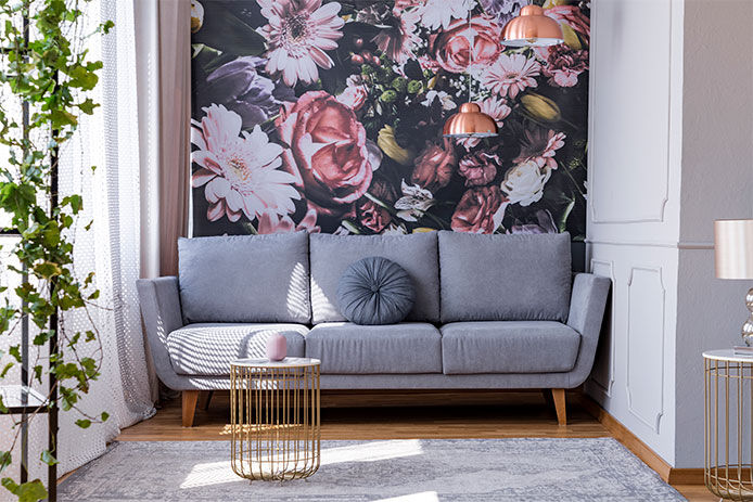 A bold floral wallpaper behind living room couch on an accent wall