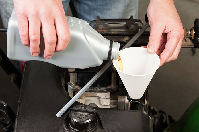 Pouring oil into a funnel and into the snowblower oil reservoir