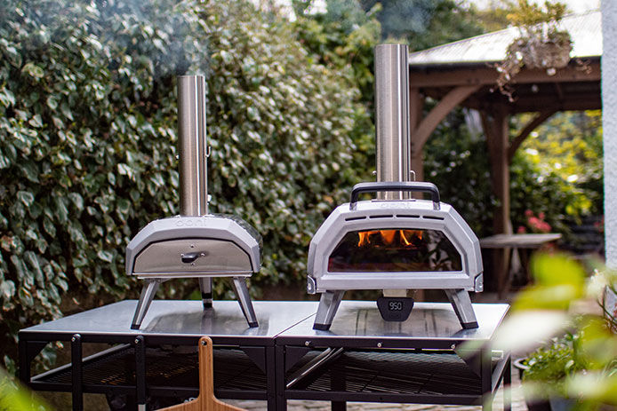 Family image of two Ooni pizza oven sitting on a table outside 