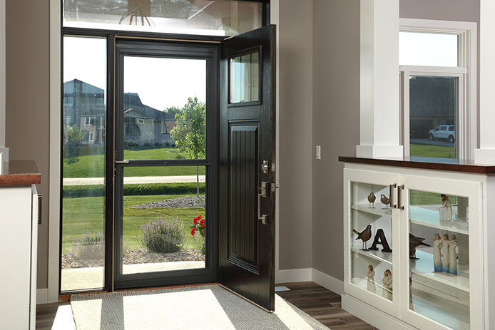 An inside view of a front foyer. The front door is open and a. storm door is shut.