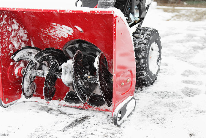 A snowblower has just finished clearing the driveway during a winter snow storm as falling snow continues to swirl.