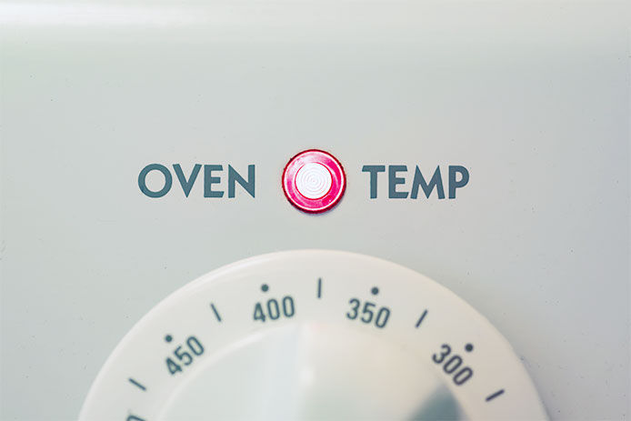 Close-up of the temperature dial and the oven temp light on an oven