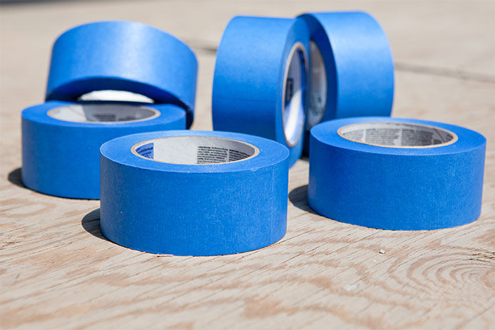 six rolls of blue painters tape sitting on a wooden surface 