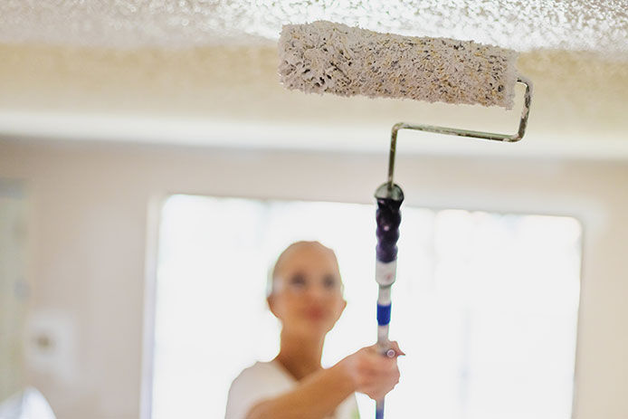 A woman painting a textured ceiling