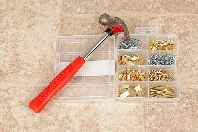 Image of a red hammer a pictre frame hanging kit with nails and hangers