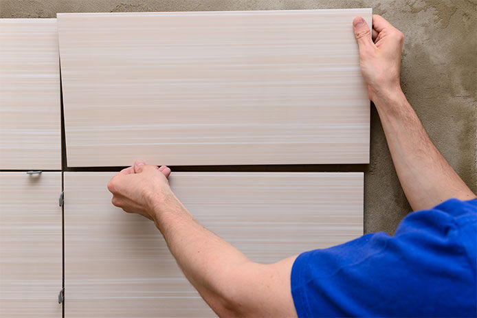 Man placing tiles onto shower wall