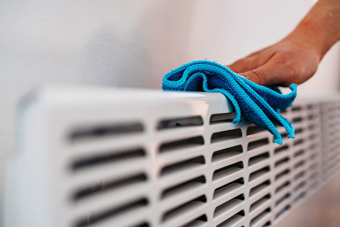 Cleaning Electric Panel Heater / Norwegian radiator with wet rag, close up.