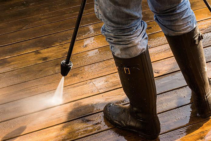 Cleaning Patio Decking with pressure washer and rubber boots on.