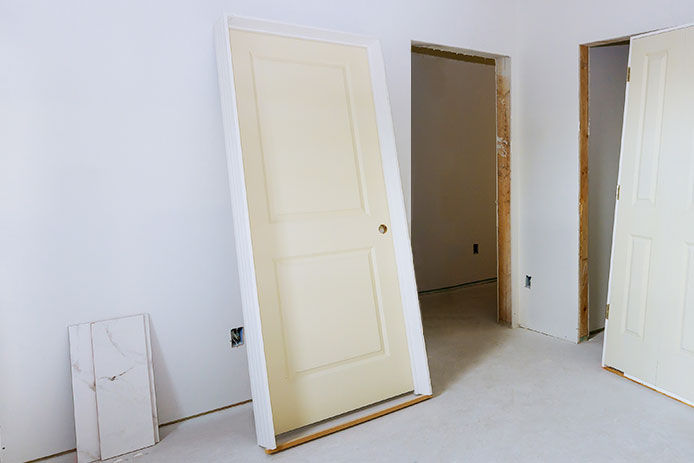 A prehung door resting up against a bedroom wall ready to be installed 