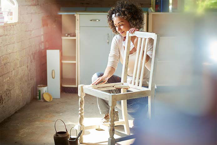 Woman sanding down a wooden kitchen chair