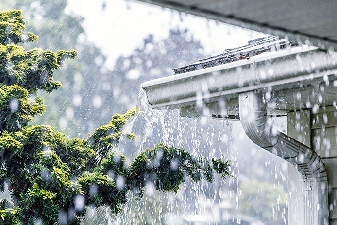 Rain downpouring, and water flowing over the gutters on a house