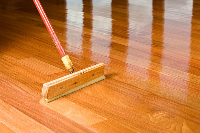 Refinishing harwood floors with a push brush with a stain sponge on the end