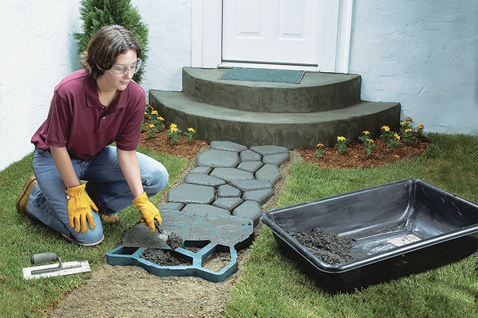 A woman making a walking path to her front door using the Quikrete WalkMaker form 