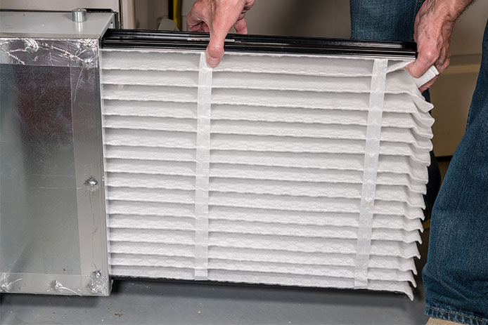 Person replacing their old air filter with a new one