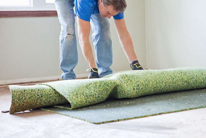 Man rolling up green carpet padding