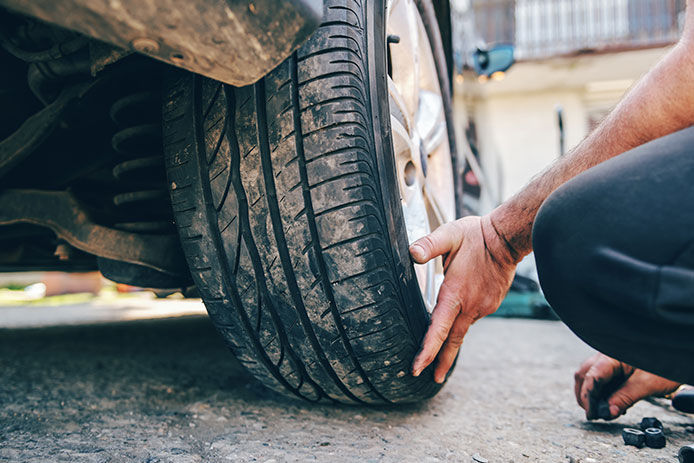 Man has his hands on the bottom of a tire steadying it