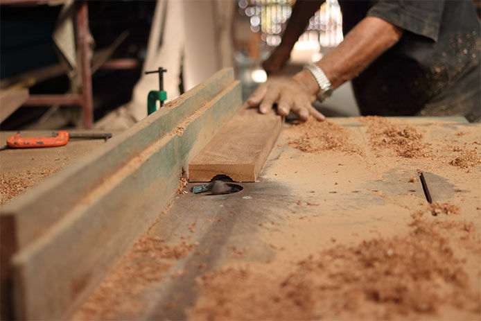 A man feeding a peice of wood into a router