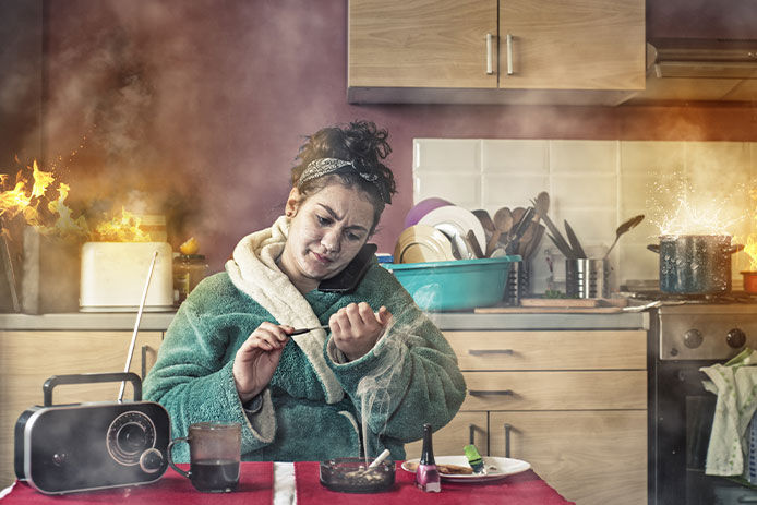 A woman sitting at a kitchen table with fire behind her