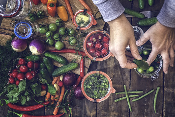 Preserving organic vegetables in jars like carrots, cucumbers, tomatoes, chilis, paprika and radishes.