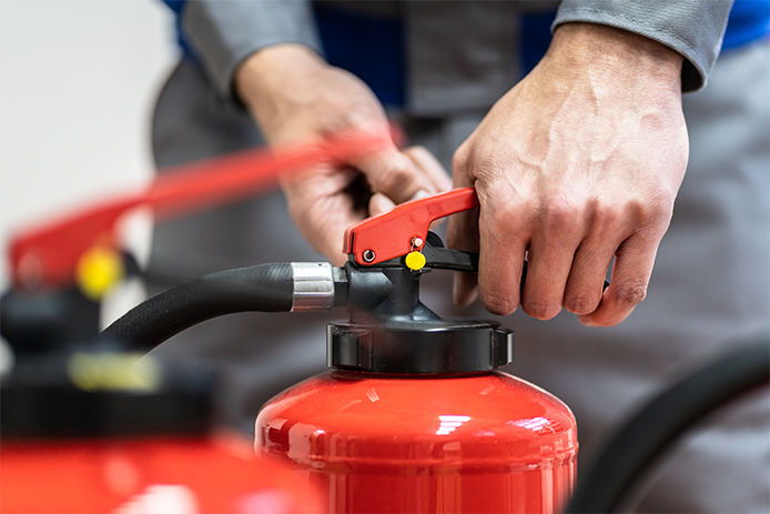 Person squeezing the lever of a fire extinguisher, close-up