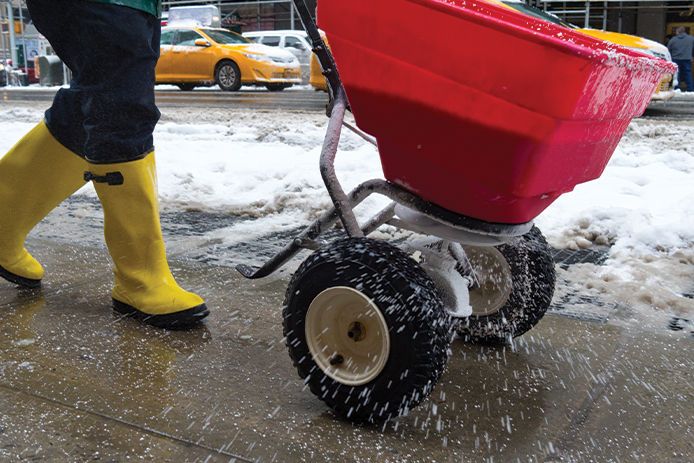 Spreading ice melt on sidewalk