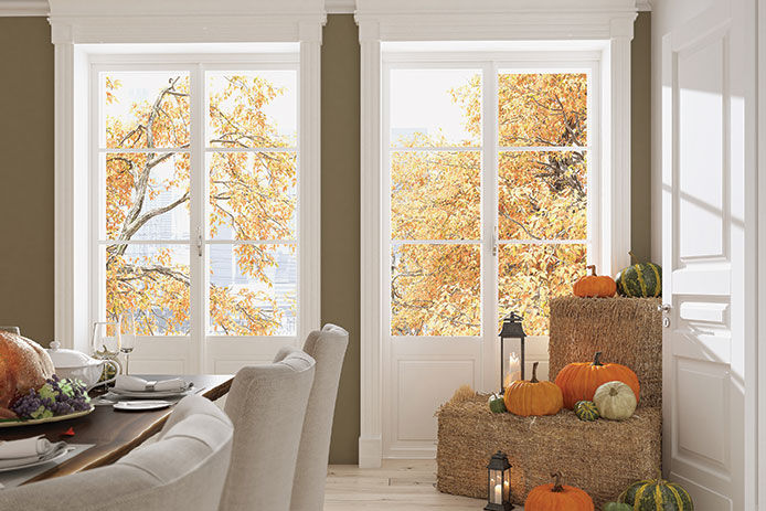 Open living room windows letting in natural light with dark olive walls decorated for fall