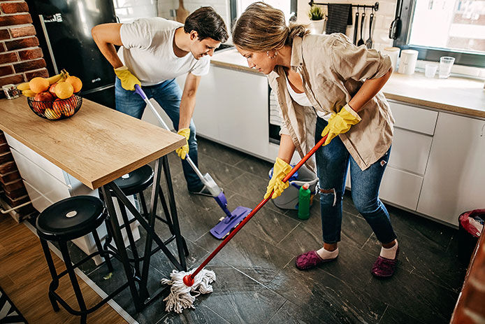 A man and a woman scrubbing a kitchen floor