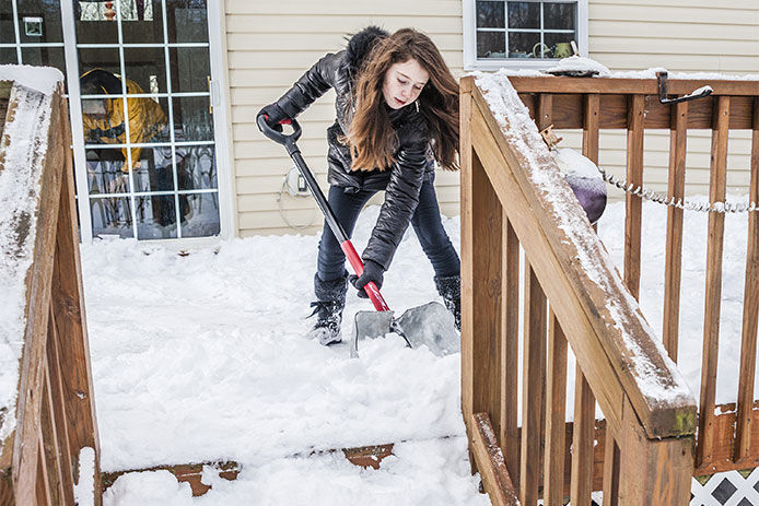 A woman shoveling snow off a deck