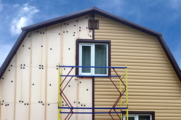 Adding beige siding to a barn style house using scaffloding 