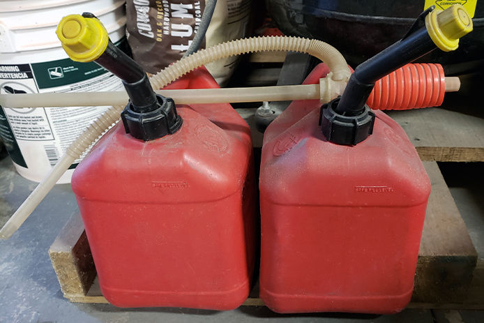 A siphon laying across two gas cans