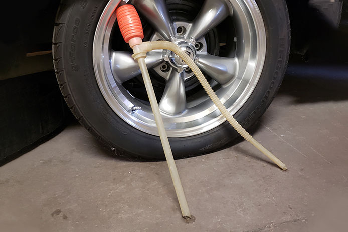 A siphon pump leaning on a tire