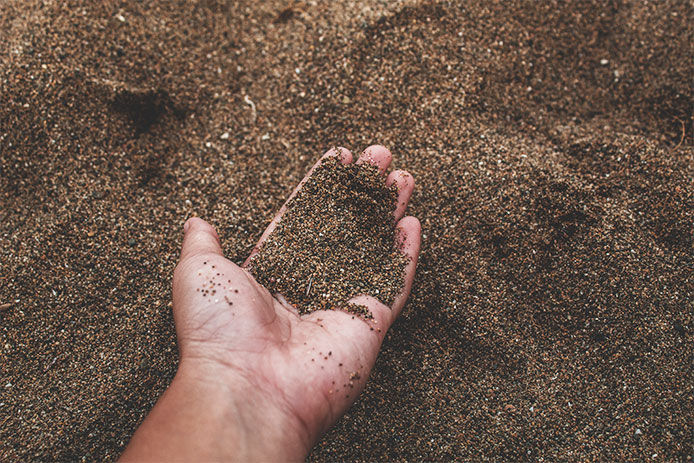 Person holding a handful of sandy soil