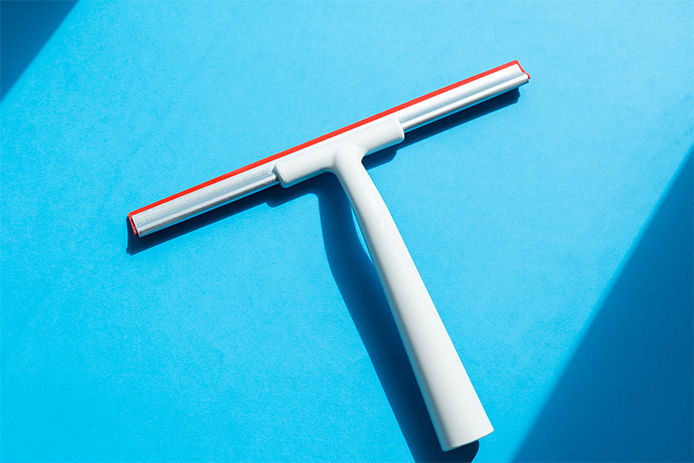 Rubber squeegee for cleaning window on the blue background, concept for spring cleaning,