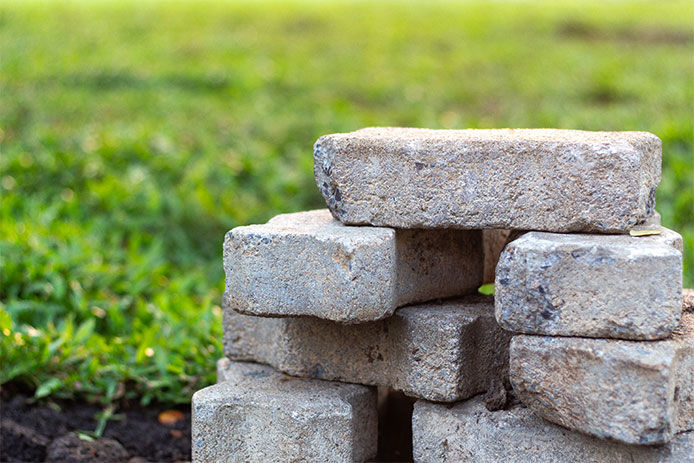 A stack of gray bricks sitting in a green lawn
