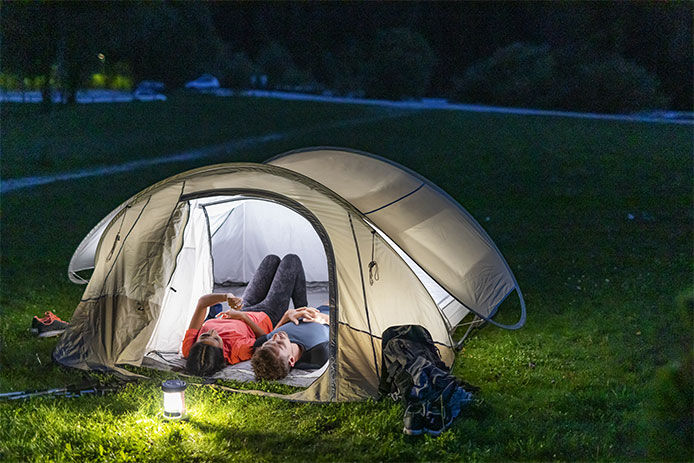 A man and a woman laying in a tent