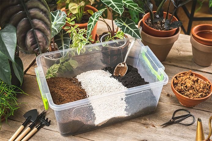 Plastic container with the soil mixing ingredients, peet moss, perlite, gardening soil, and coco husk chips.