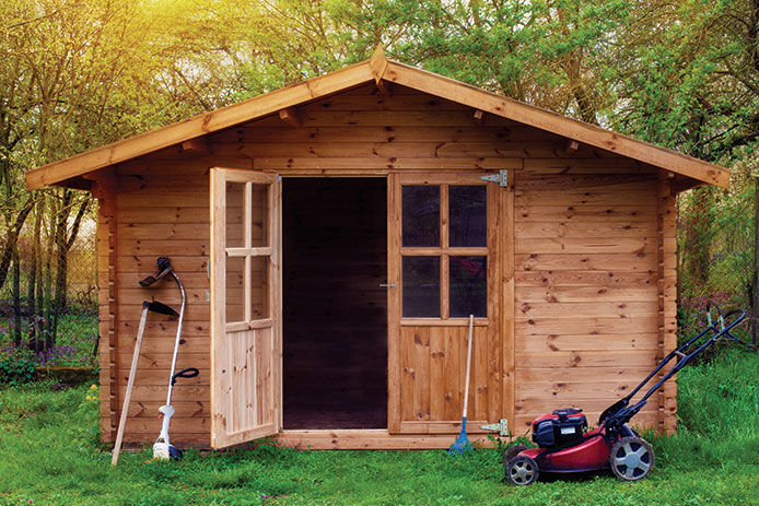 A wooden garden shet with a mower and string trimmer outside