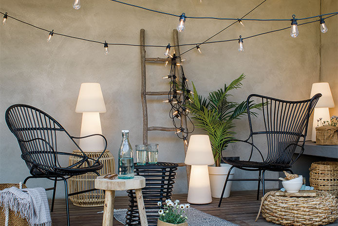 A lifestyle image of a boho style patio with black string lights and house plants