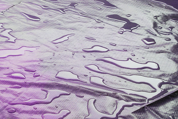 water drops on tarpaulin surface and beautiful purple color effect. shiny and wet banner material