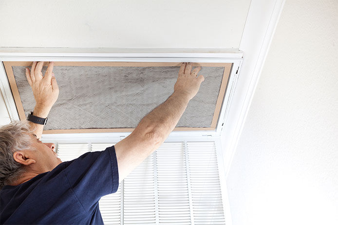 Man replacing dirty air conditioning filter at home.