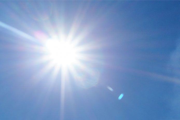 An image of the sun in the sky shining down on a summer day